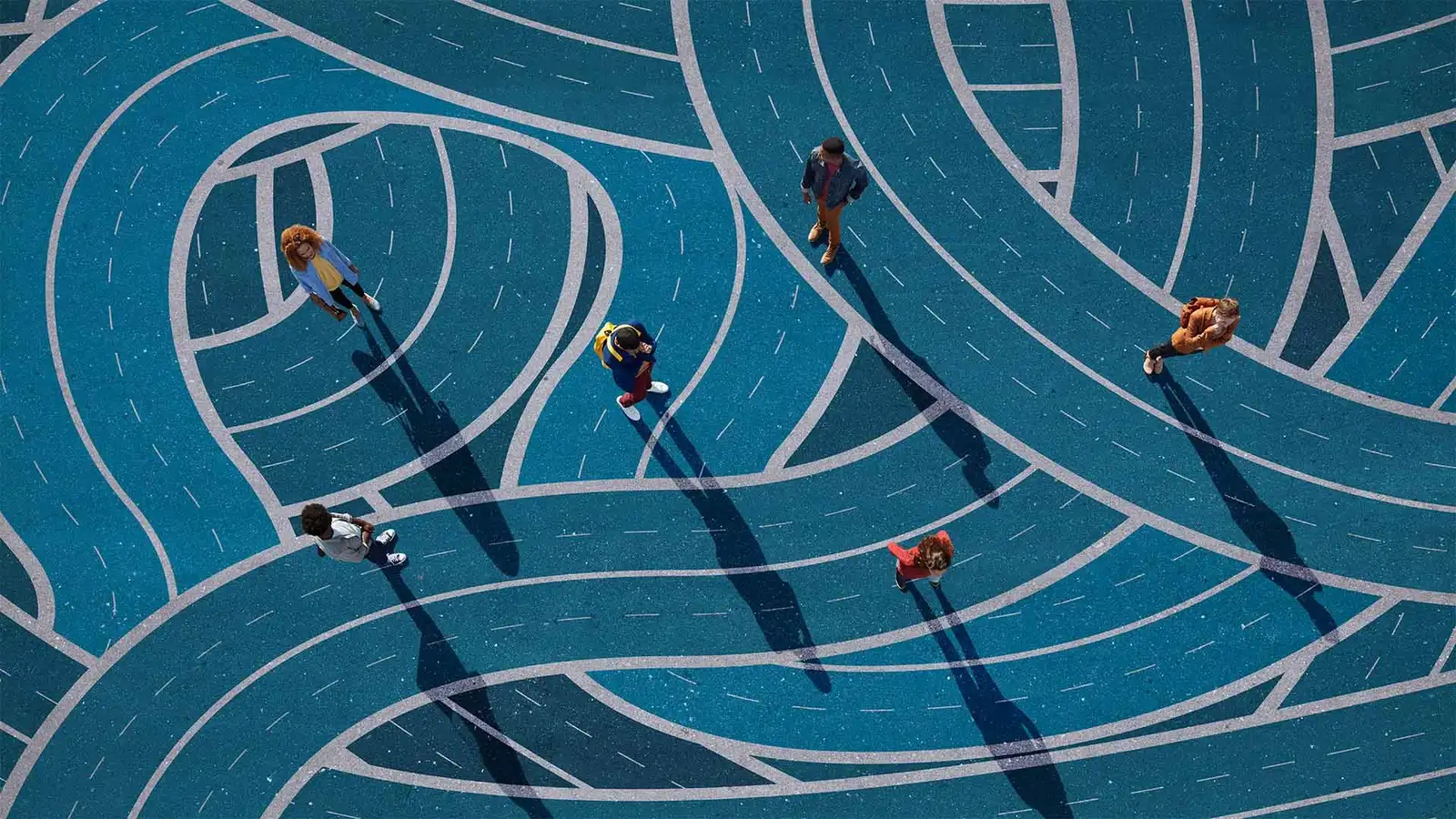 An overhead view of six young people crossing a wide expanse of blue asphalt painted with looping, interlocking roads, each walking a different route.